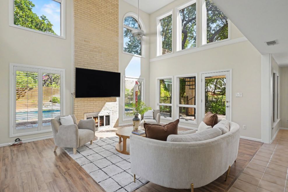 Two-story living room staged with curved seating and warm neutral accents