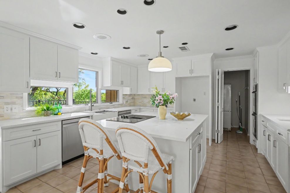 Bright white kitchen with staged island and woven counter stools