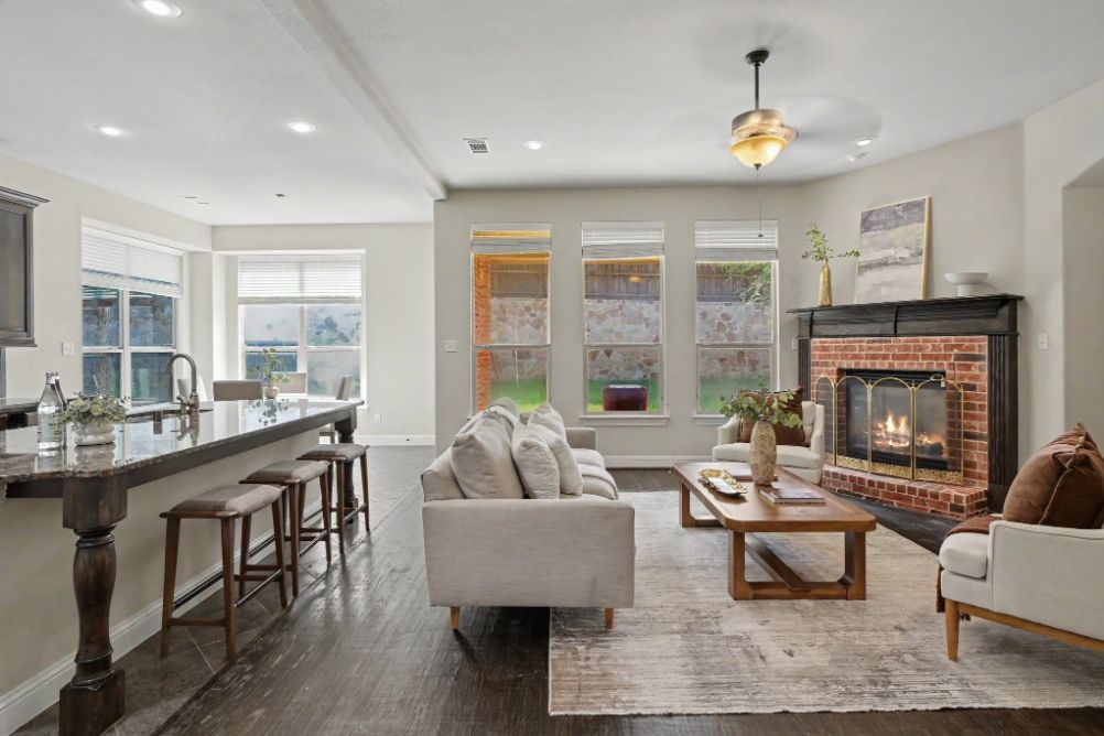 Open living room staged with warm wood furniture and a brick fireplace